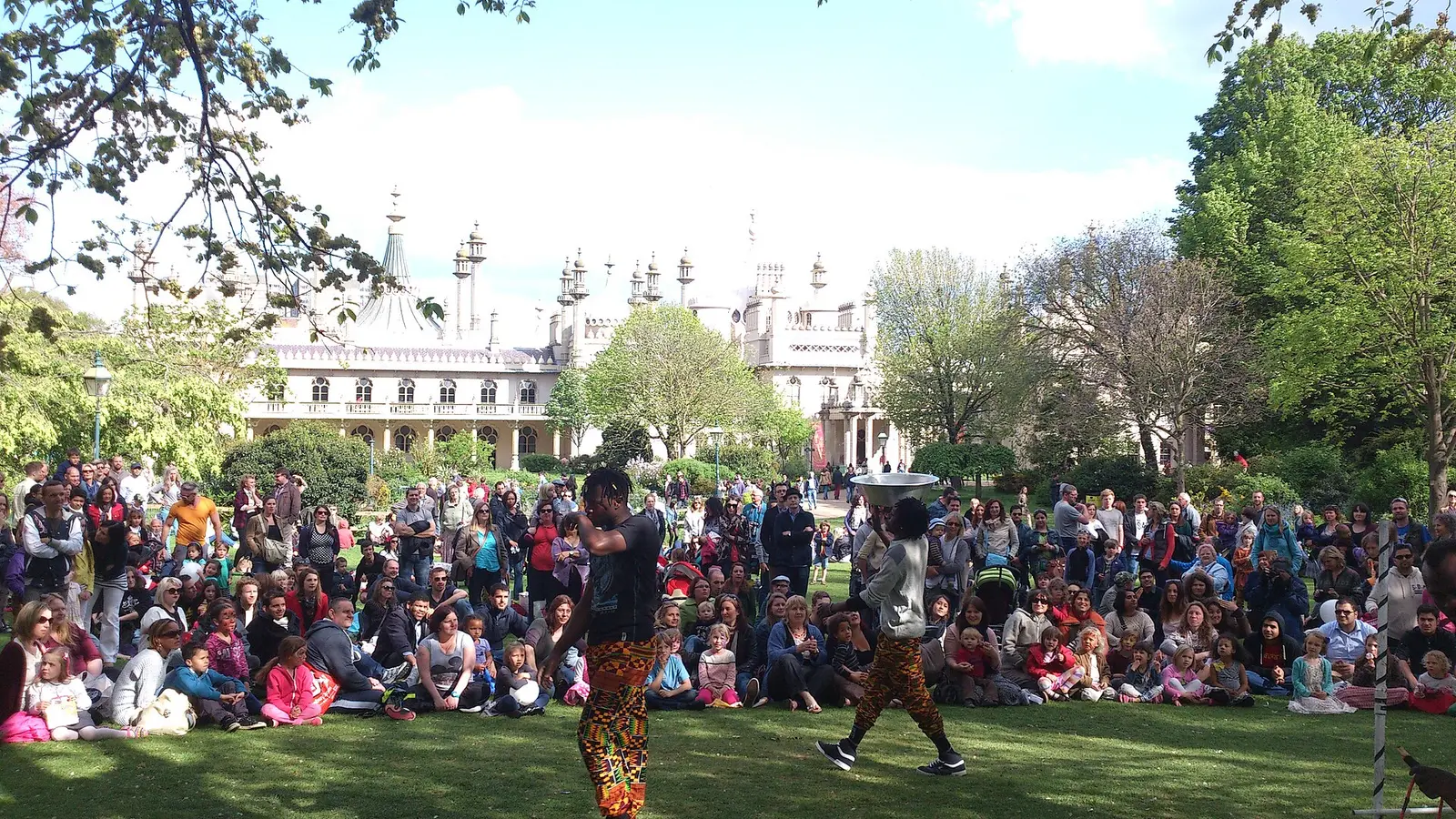 Children watch performers on the lawn of Pavilion Gardens during Fringe City at Brighton Fringe, the Royal Pavilion behind