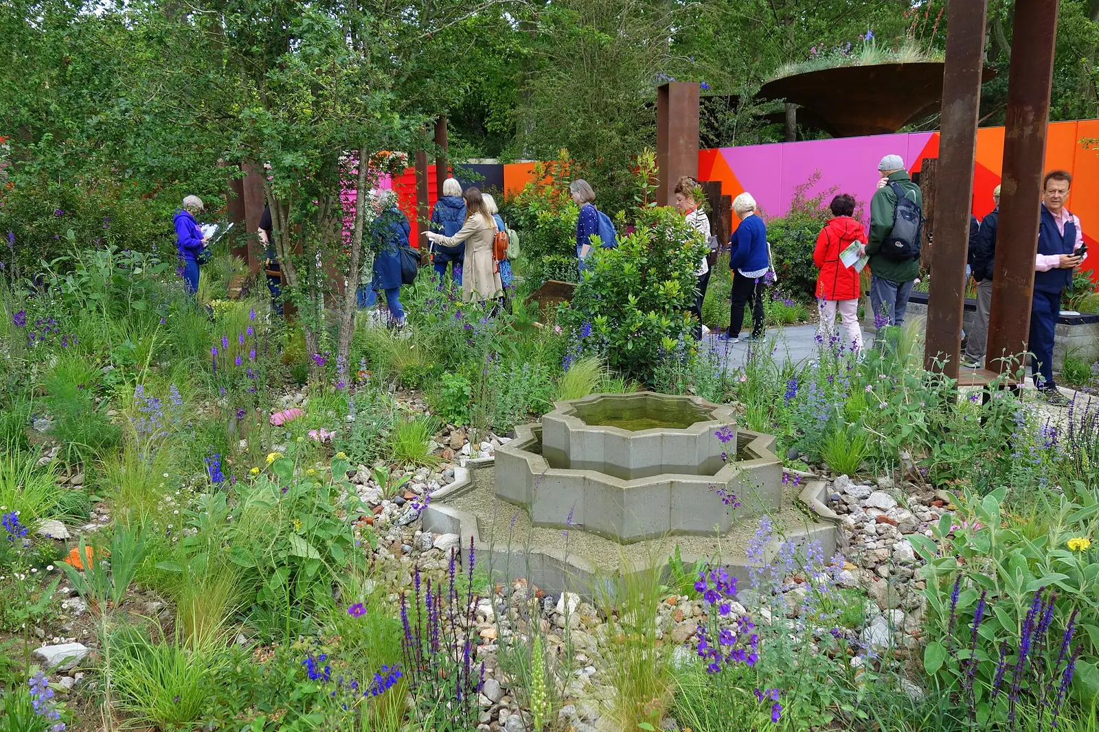 Visitors walk past a planted garden with a stone fountain at the Chelsea Flower Show in 2024