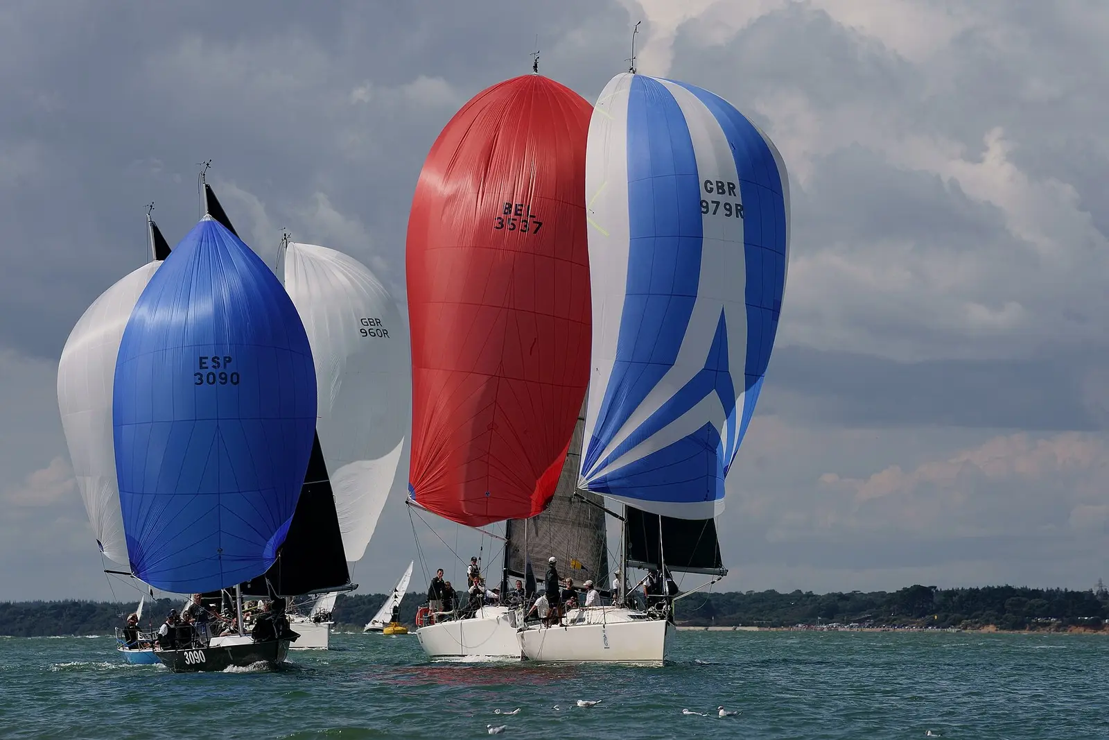 Yachts under red and blue spinnakers racing at Cowes Week in 2019