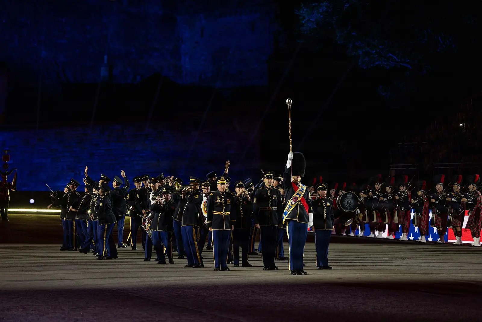 A military band marches across the floodlit Esplanade at the Royal Edinburgh Military Tattoo at night