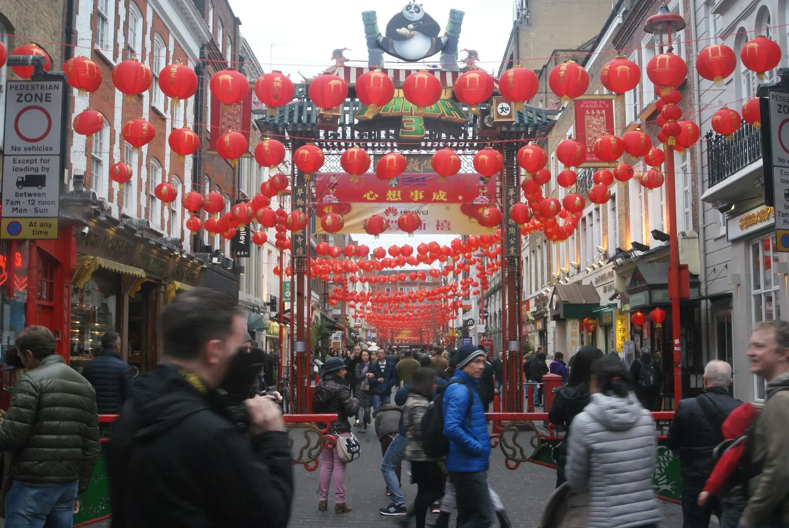 Crowds beneath red lanterns on Wardour Street in London's Chinatown at Chinese New Year