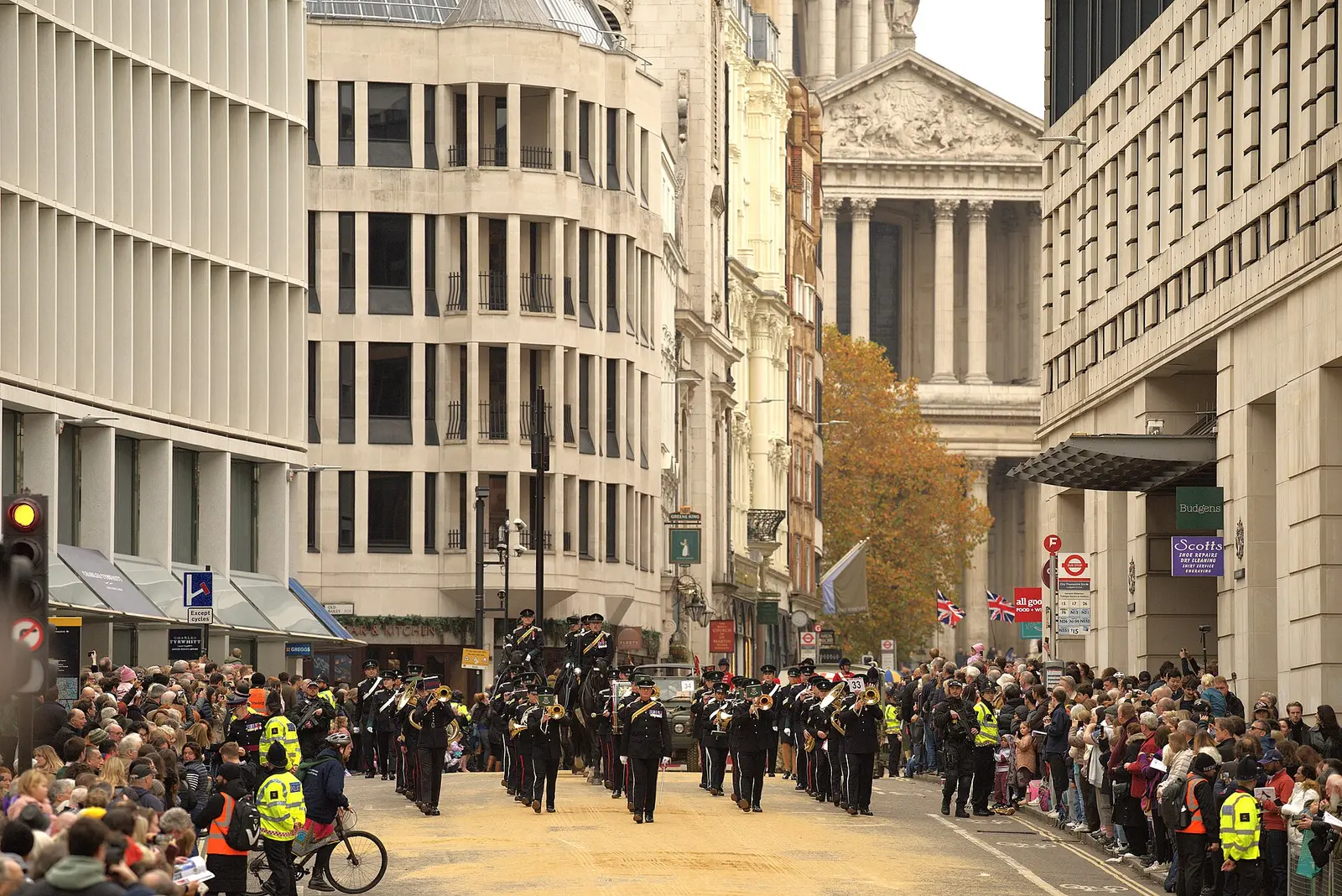 Crowds line a City of London street as the Lord Mayor's Show procession passes with St Paul's Cathedral in the distance