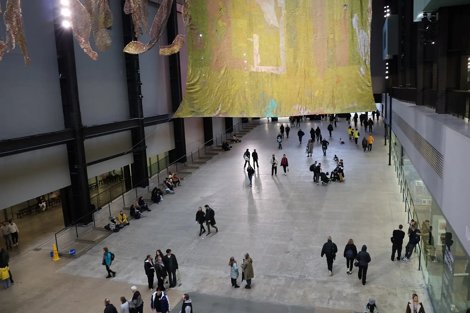 Visitors in the Turbine Hall at Tate Modern beneath a hanging installation