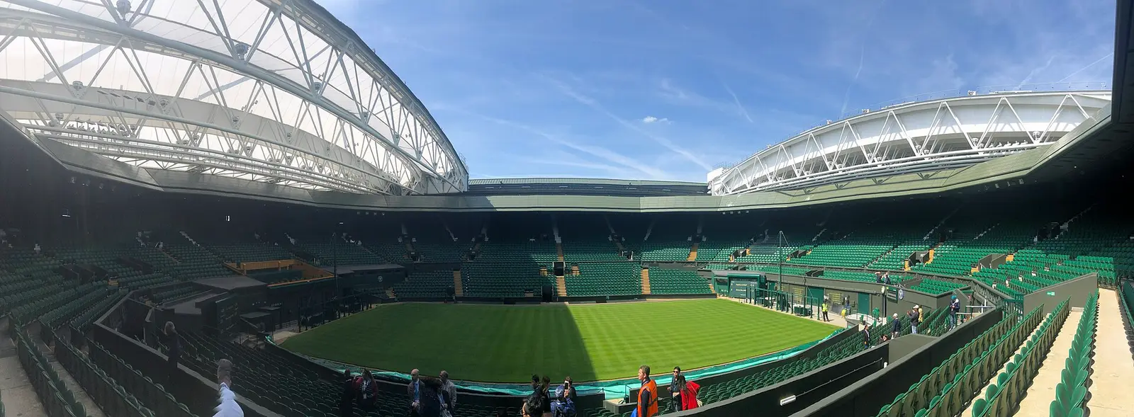 Centre Court at Wimbledon with its retractable roof open and the grass court under a blue sky